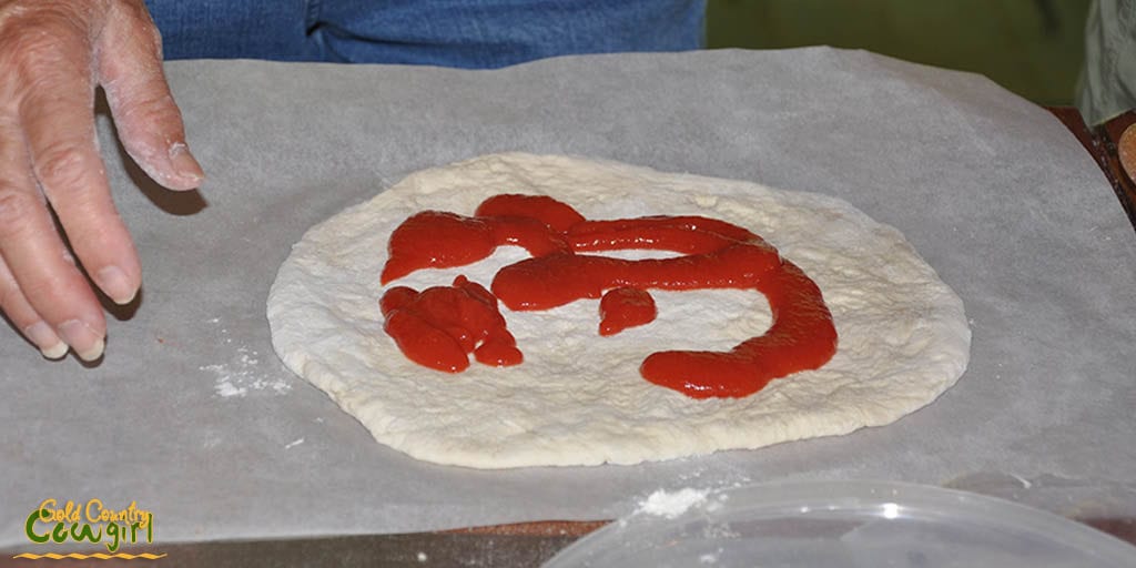 Putting sauce on the pizza dough