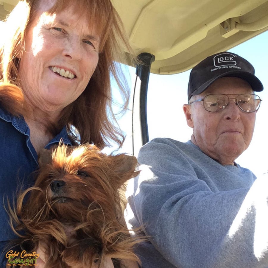 man and woman holding dog in golf cart