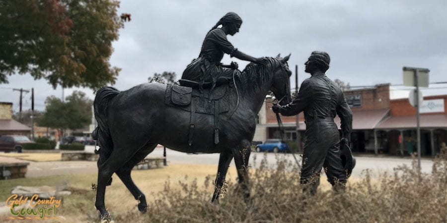 bronze statue of woman on horse and man standing at horse's head