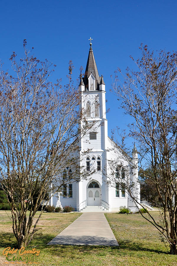 white church behind tree branches - St. John the Baptist Ammannsville, one of the four painted churches of Schulenburg