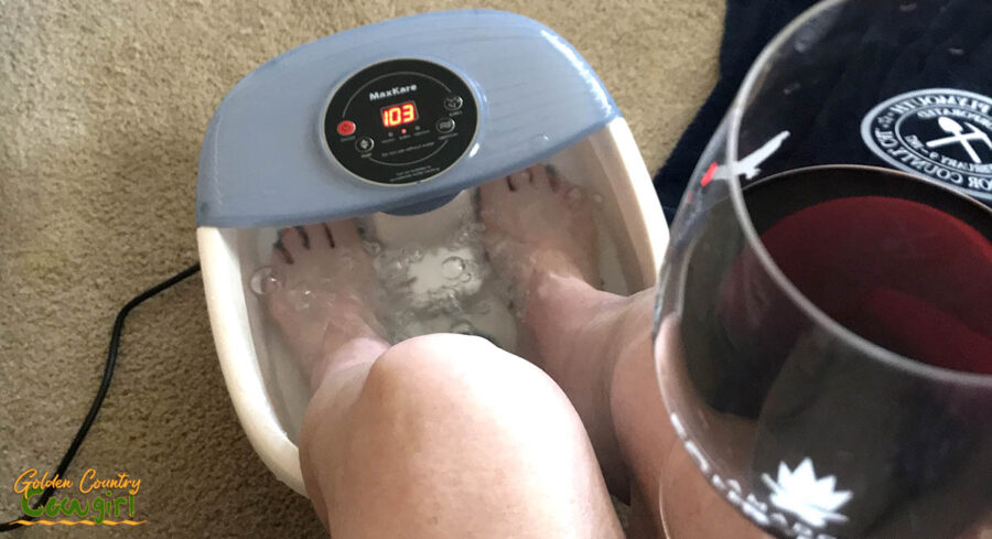 soaking feet in a foot bath holding a glass of wine