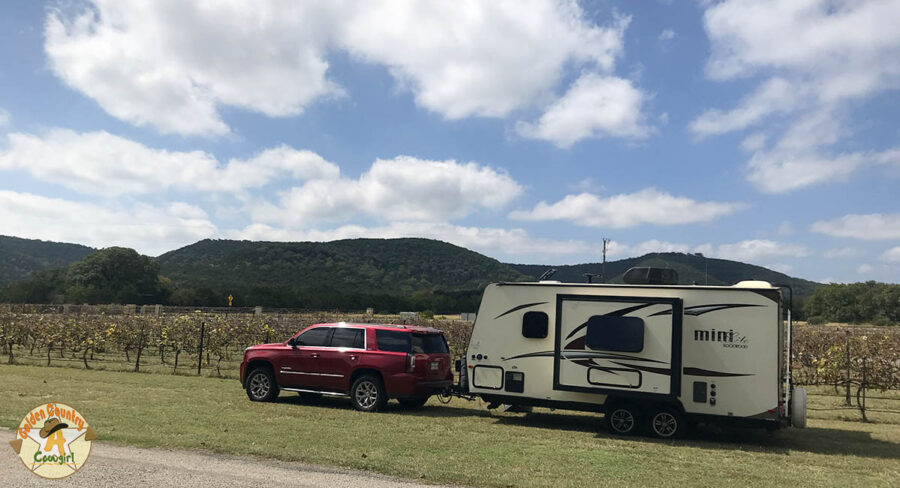 SUV and trailer parked in front of grapevines at Lost Maples Winery