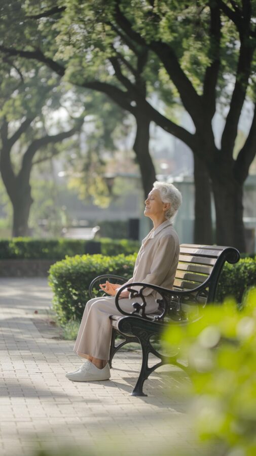 An older woman is sitting on a bench in meditation.