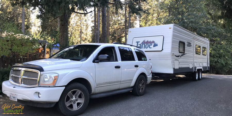 an SUV and travel trailer driving down the street